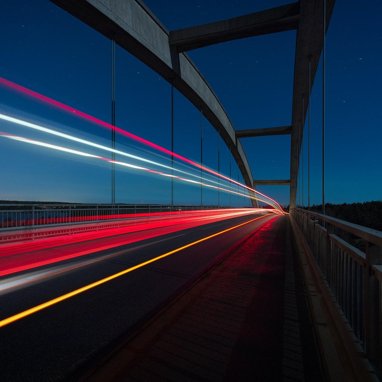 gray suspension bridge with streaks of light time lapse photography